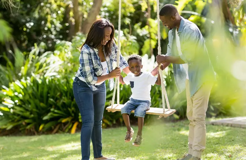 Mom and Dad pushing son on swing