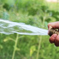 Someone watering the grass, close up on the hand